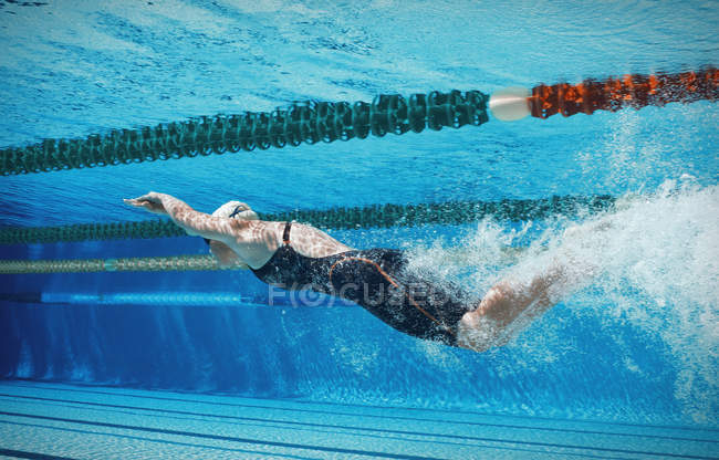 Swimmer racing underwater at pool — Stock Photo