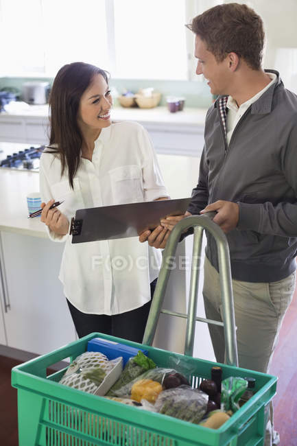 Woman signing for delivery in kitchen — Stock Photo