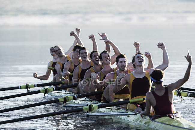 Rowing team celebrating in scull on lake — Stock Photo
