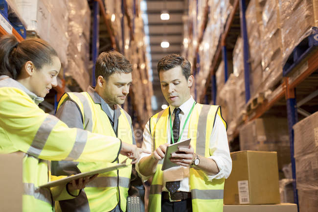 Businessman and workers talking in warehouse — Stock Photo