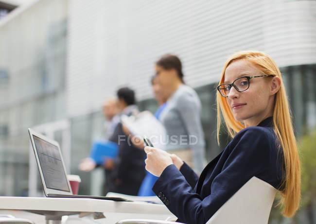 Geschäftsfrau arbeitet am Tisch vor Bürogebäude — Stockfoto