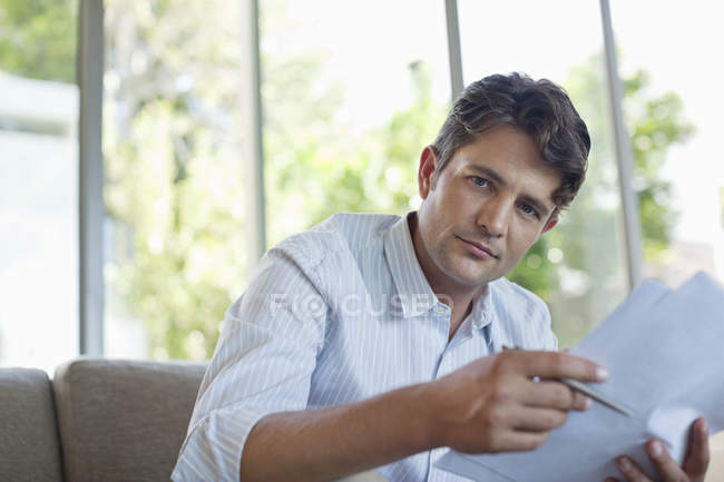 Homme d'affaires lisant des papiers sur canapé — Photo de stock