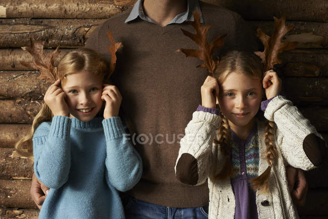 Meninas usando folhas como chifres com pai por parede — Fotografia de Stock
