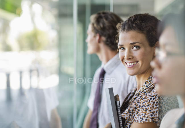 Businesswoman smiling at modern office window — Stock Photo
