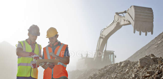 Workers reading blueprints in quarry — Stock Photo