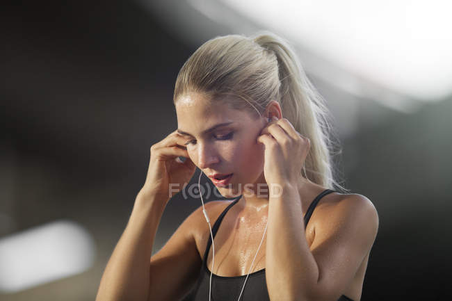 Mulher exercitando e ouvindo fones de ouvido — Fotografia de Stock