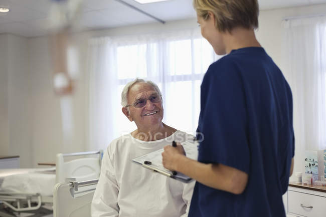 Медсестра розмовляє зі старшим пацієнтом у лікарні — стокове фото