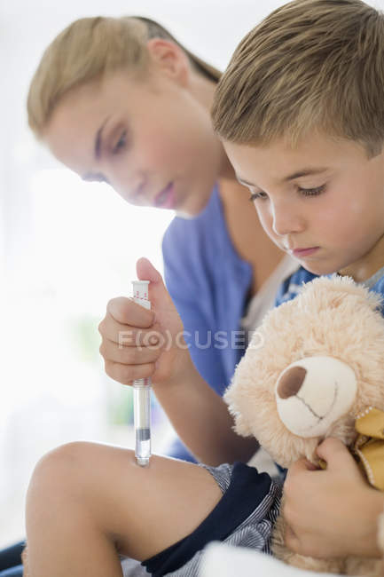 Mother giving son injection in leg — Stock Photo