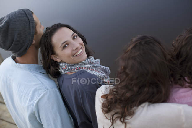 Портрет улыбающейся женщины, сидящей с друзьями у озера — стоковое фото