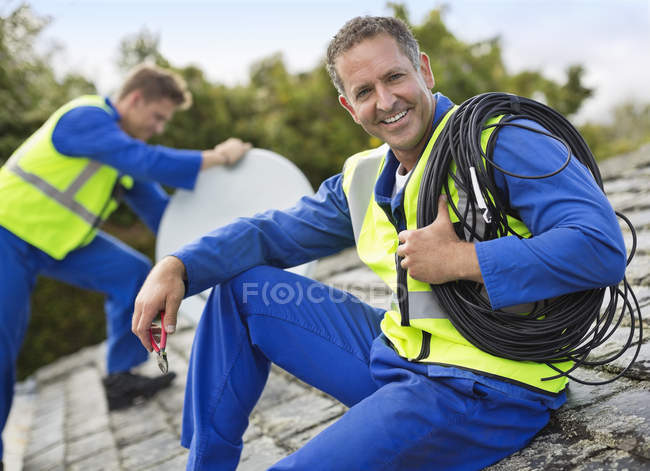 Workers installing satellite dish on roof — Stock Photo
