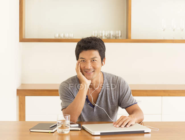 Jeune homme attrayant écoutant des écouteurs à table — Photo de stock