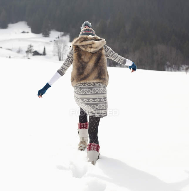 Femme marchant dans un champ enneigé — Photo de stock