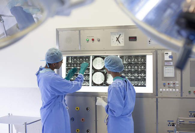Cirujanos examinando rayos X en hospital moderno - foto de stock