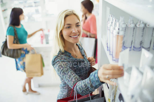 Mulher examinando produtos de cuidados com a pele na farmácia — Fotografia de Stock