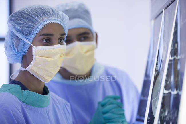 Cirujanos examinando rayos X en la habitación del hospital - foto de stock