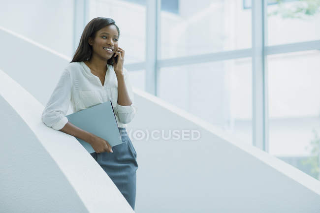 Donna d'affari che parla al cellulare sulle scale dell'edificio dell'ufficio — Foto stock