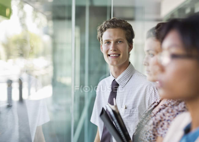 Businessman smiling at modern office window — Stock Photo