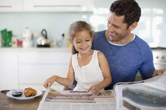 Отец и дочь читают газету за завтраком — стоковое фото