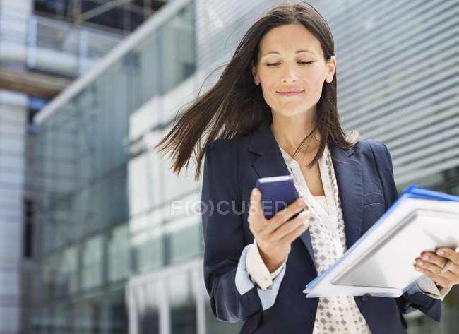 Businesswoman using cell phone in office — Stock Photo