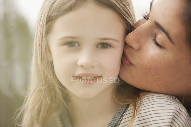 Close up portrait of mother kissing daughter?s cheek — Stock Photo