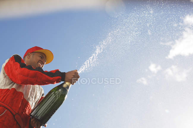 Racer spraying bottle of champagne outdoors — Stock Photo