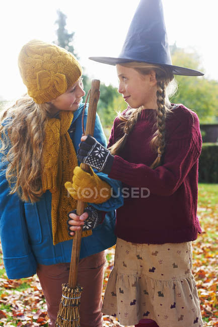 Girls playing with witch's hat and broom outdoors — Stock Photo