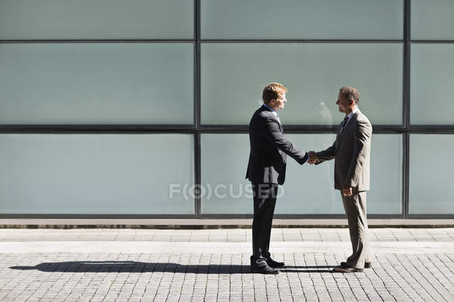 Businessmen shaking hands outdoors of modern office — Stock Photo