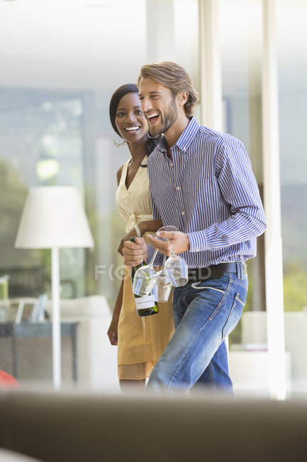 Couple carrying wine bottle and glasses — Stock Photo