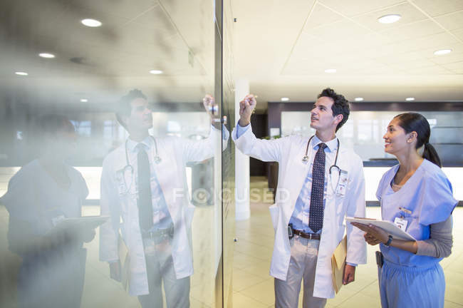 Médico e enfermeiro conversando no corredor hospitalar — Fotografia de Stock