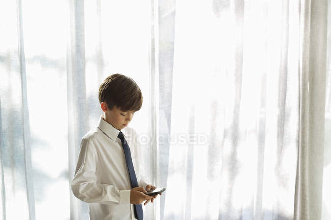 Хлопчик у сорочці та краватці за допомогою мобільного телефону — стокове фото