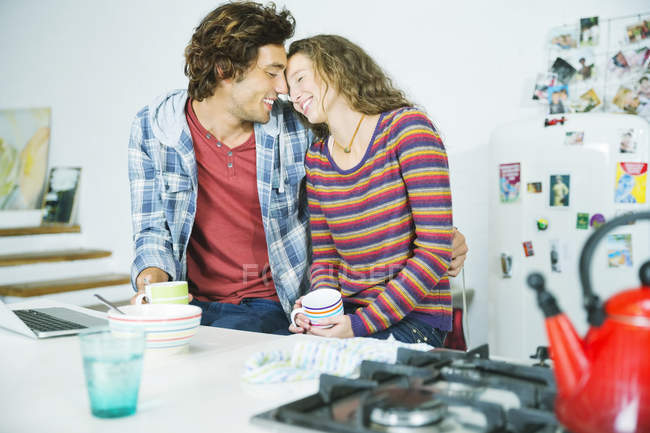 Jovem casal relaxar juntos na cozinha — Fotografia de Stock