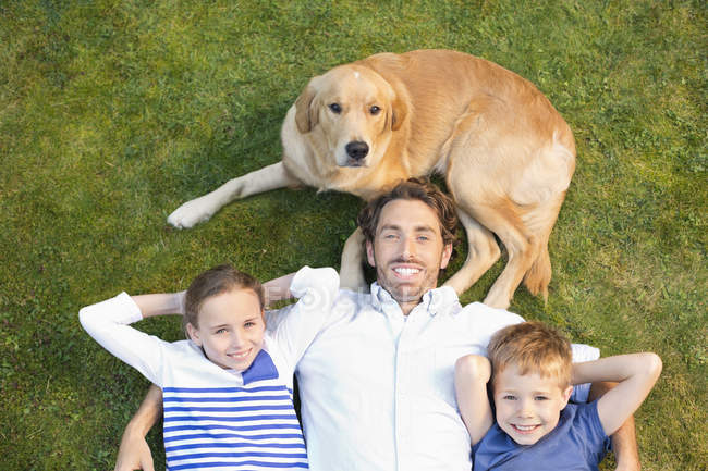 Family relaxing together with dog on lawn — Stock Photo