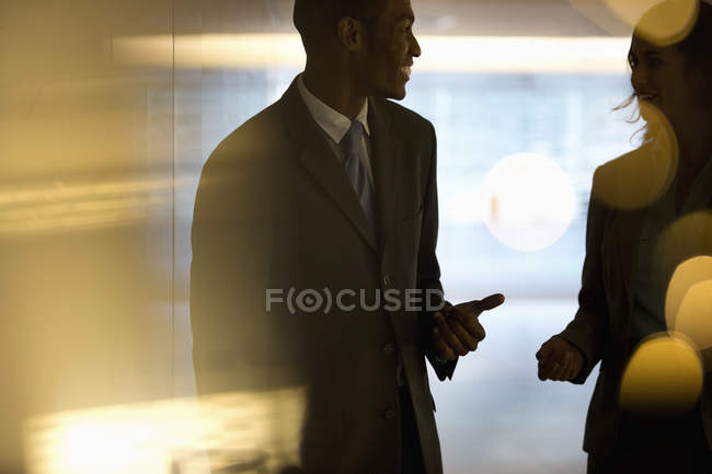 Бізнесмен і бізнес-леді розмовляють у лобі в сучасному офісі — стокове фото