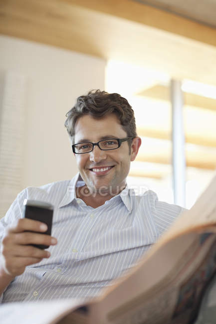 Uomo che utilizza il telefono cellulare sul divano — Foto stock