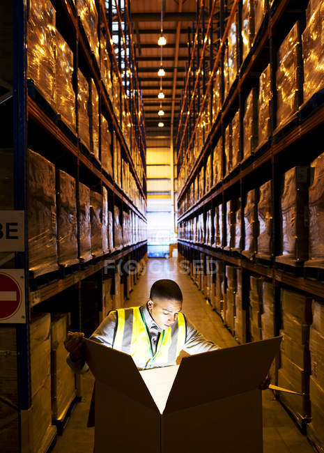 Trabajador abriendo caja brillante en el almacén - foto de stock