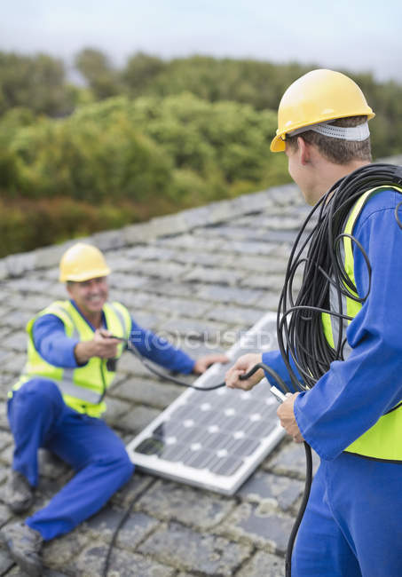 Hábiles trabajadores caucásicos instalando panel solar en el techo - foto de stock