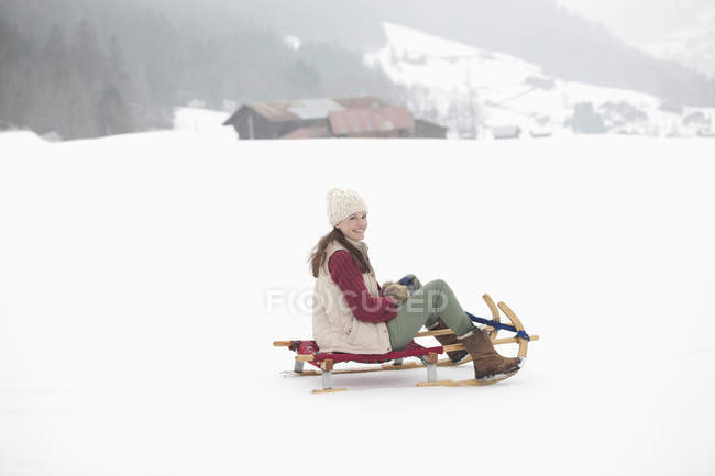 Retrato de mulher sorrindo trenó no campo nevado — Fotografia de Stock