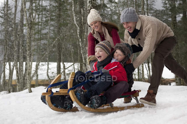 Luge familiale heureuse dans les bois enneigés — Photo de stock