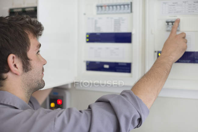 Eletricista caucasiano hábil examinando painel de controle — Fotografia de Stock