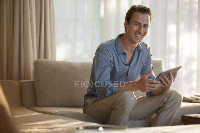 Homem usando computador tablet no sofá — Fotografia de Stock