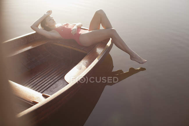 Donna serena prendere il sole in barca sul lago — Foto stock