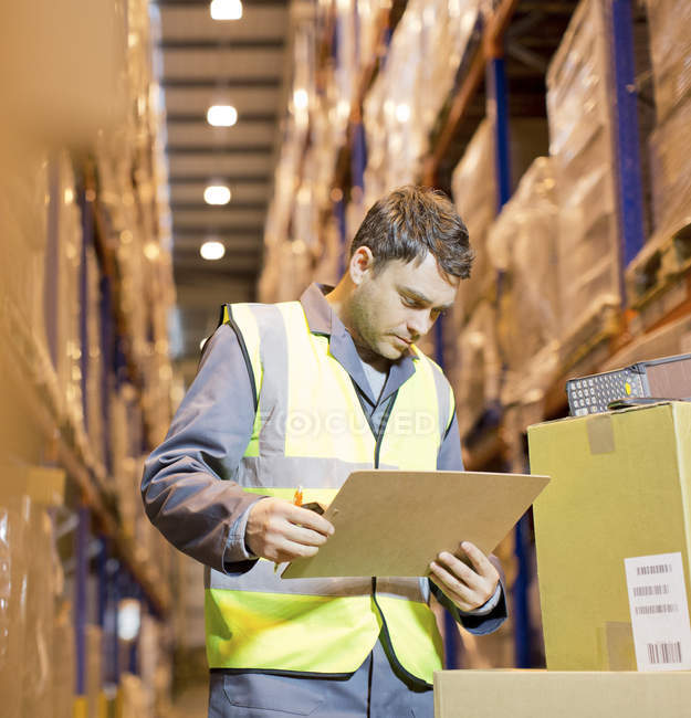 Worker reading clipboard in warehouse — Stock Photo