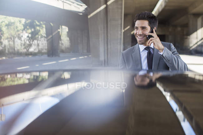 Businessman talking on cell phone in parking garage — Stock Photo