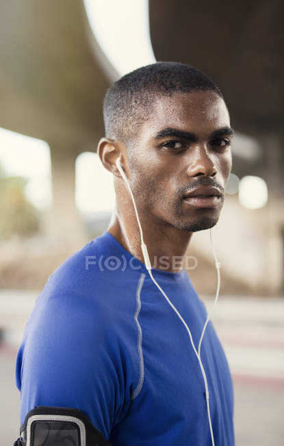Hombre con auriculares haciendo ejercicio en la calle de la ciudad - foto de stock