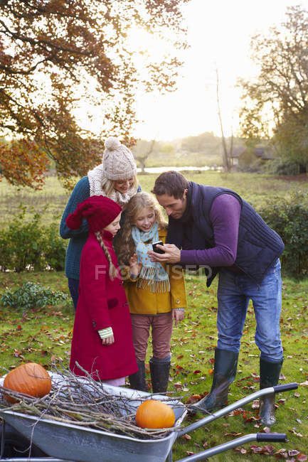 Family using cell phone together outdoors — Stock Photo