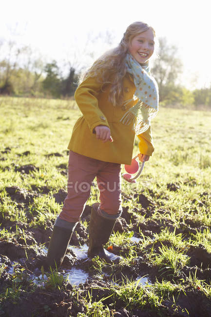Chica vadeando en el campo fangoso - foto de stock