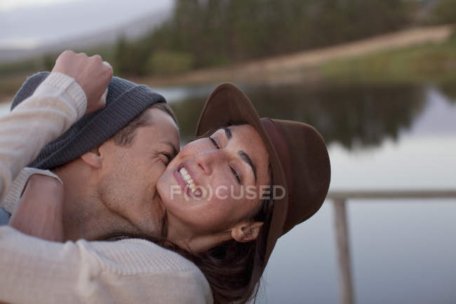 Энтузиастичная счастливая пара обнимается на берегу озера — стоковое фото