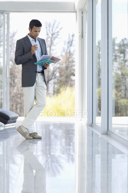 Бизнесмен читает газеты в современном офисе — стоковое фото