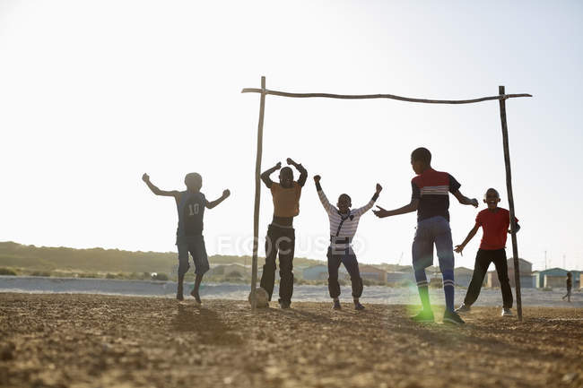 African boys playing soccer together in dirt field — Stock Photo