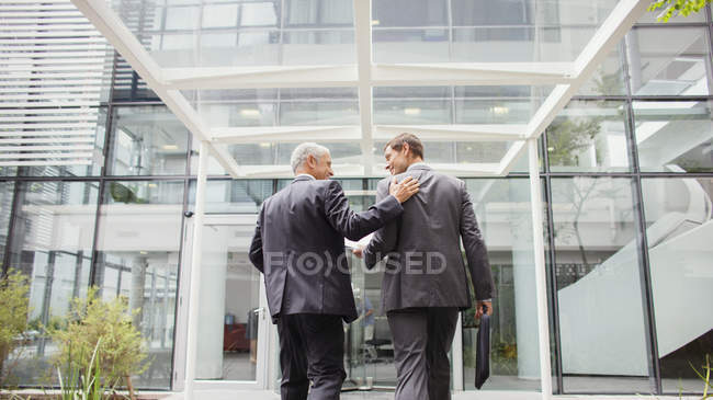 Задний вид на бизнесменов, входящих в офисное здание вместе — стоковое фото